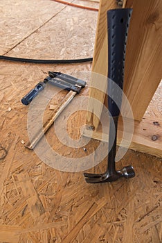 The carpenter`s hammer and the ribbing lying on the OSB board