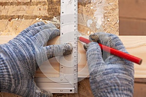 Carpenter`s hands with a corner and a pencil mark on the board