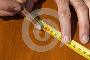 Carpenter`s hands indicate the dimension on the board with a pencil and an angle.