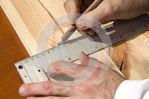 Carpenter`s hands indicate the dimension on the board with a pencil and an angle.