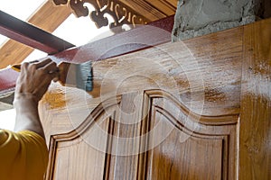Carpenter s hands paintbrush varnish to wood door