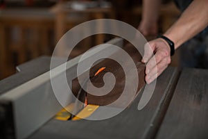 Carpenter`s hands saw a bar of wood on the machine with a circular saw.