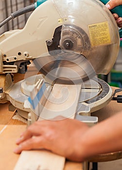 Carpenter`s hands on wood at table saw making a cut