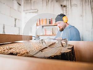 Carpenter`s safety goggles on wood stump. carpentry workshop. wood stump processing