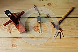 Carpenter`s for woodworking. Old Hammer and nail and wood plane and Measuring tape on texture wooden background