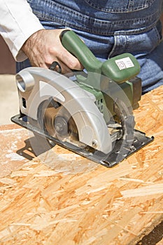 Carpenter`s workshop. Carpenter cuts the OSB