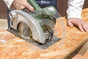 Carpenter`s workshop. Carpenter cuts the OSB