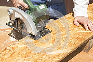 Carpenter`s workshop. Carpenter cuts the OSB