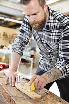 Carpenter sanding a guitar neck in wood at workshop