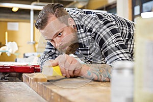 Carpenter sanding guitar neck in wood at workshop