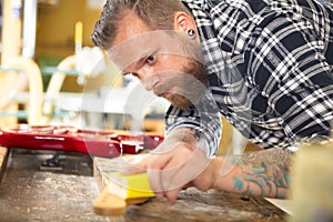 Carpenter sanding guitar neck in wood at workshop