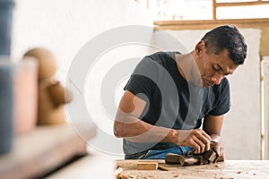 carpenter sanding a piece of wood. craft procedures with wood. Colombian man in his workshop