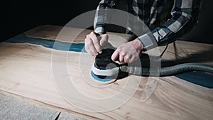 Carpenter sanding wood and resin countertops in workshop
