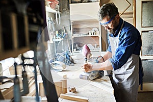 Carpenter Sanding Wood in Workshop