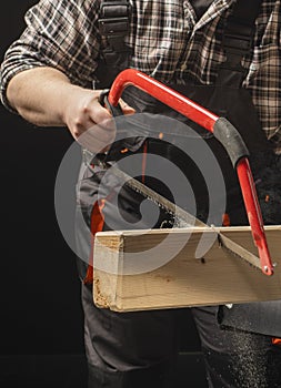 Carpenter sawing a board with a hand wood saw