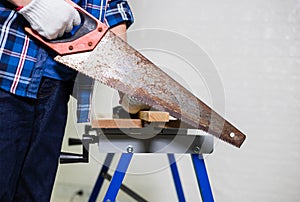 Carpenter sawing a board with a hand wood saw, man working cutting plank with handsaw