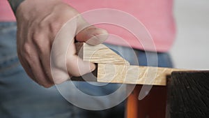 Carpenter saws a piece from a oak board with a hand saw. carpenter sawing a piece from a oak board using a hand saw for wood. Hand