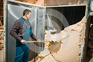 Carpenter with shovel removes sawdust, woodworking