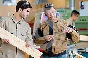 carpenter showing tool to apprentice