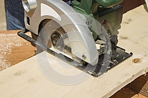 Carpenter slashes the board using an electric saw