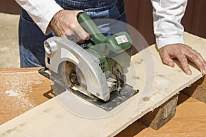 Carpenter slashes the board using an electric saw
