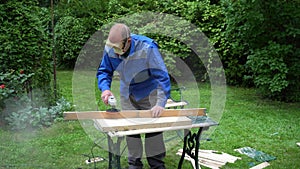 Carpenter smoothing renewing plank with grinder. Male using grinder machine
