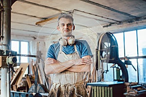 Carpenter standing in his wood workshop looking at camera