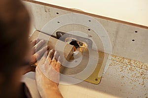 Carpenter in studio puts wood block through spindle moulder, close up