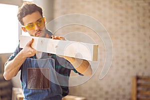 Carpenter testing wood plank evenness at workshop