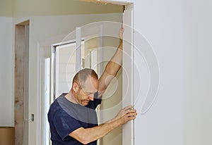 Carpenter to moldings on doors doorway framing trim, close up on hand and nail gun