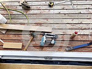 Carpenter tools lying on outdoor home deck to install wooden floor dear door jam