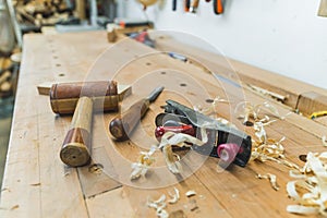 Carpenter tools - a wooden mallet, a chisel and a planer with wooden chips on the table