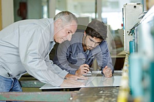 Carpenter trainees learning with boss about wood measurement