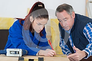 Carpenter training female apprentice to use plane