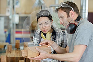 Carpenter training female apprentice to use plane