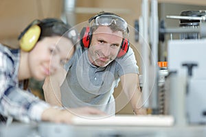 carpenter training female apprentice to use plane