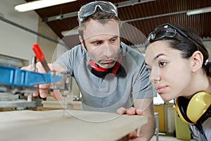 carpenter training female apprentice in workshop