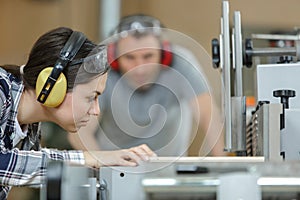 carpenter training female apprentice in workshop