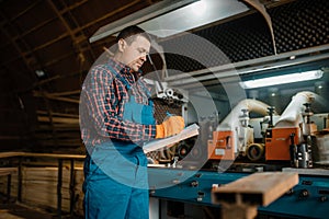 Carpenter in uniform holds notebook, lumber