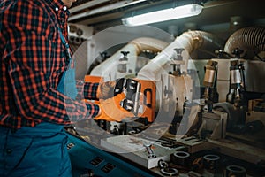 Carpenter in uniform near woodworking machine