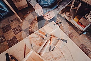 carpenter use a chisel to shapes a wooden plank.