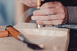 carpenter use a chisel to shapes a wooden plank.