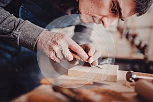 Carpenter use a chisel to shapes a wooden plank.