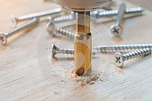 Carpenter use countersink bit to drill both a pilot hole and use countersink bit to recess the head of the screw into wood plank.