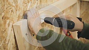 A carpenter uses a drill to drill holes in a wooden board.