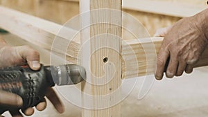 A carpenter uses a drill to drill holes in a wooden board.