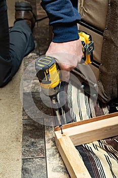 The carpenter uses a drill to tighten the screws to the plank