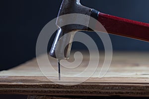 The carpenter uses a hammer to hit the nail