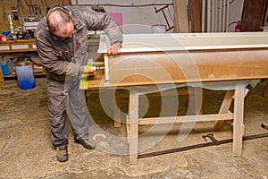 Carpenter uses hand drill, acu power tool and tightens the screws on the wooden door frame