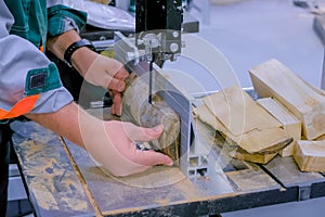 Carpenter using bandsaw tool, cutting piece of wood at workshop - close up